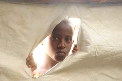 Boy child in Rwanda peeks through a tent