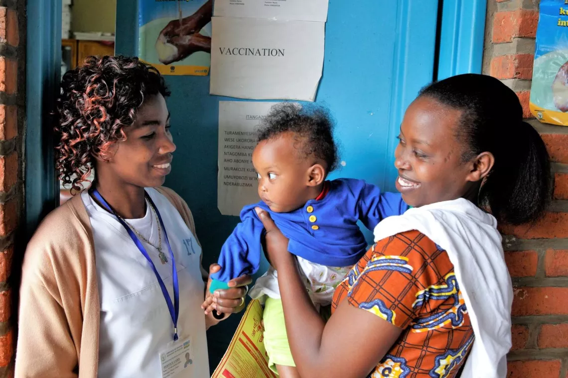 A mother and her baby son visit with their nurse outside a health centre in Rwanda.