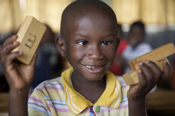 A young boy uses blocks of wood to count in a Primary 1 classroom in Rwanda.
