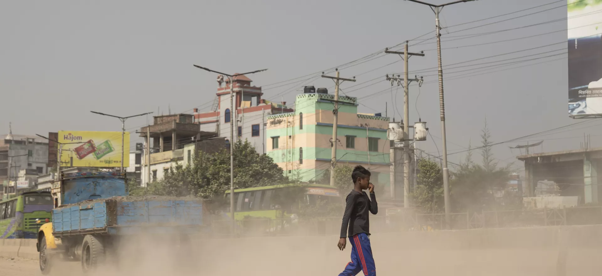 A child worker is crossing a severely polluted road in Dhaka, Bangladesh.