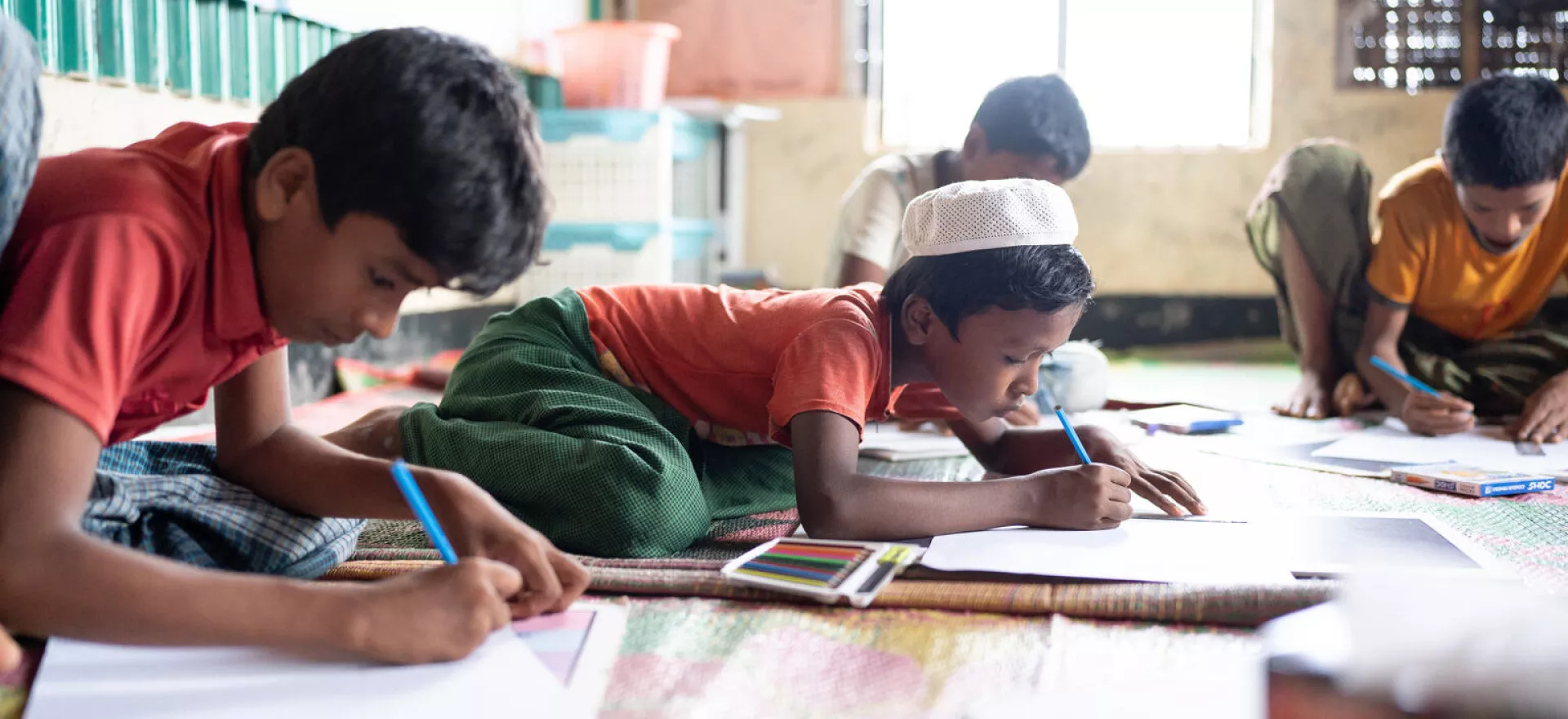 Bangladesh. A group of children draw pictures with colouring pencils during a group activity session at a Multi-Purpose Centre in a Rohingya refugee camp in Cox’s Bazar