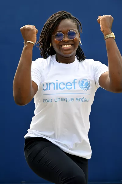 young girl jumping and smiling with a UNICEF T-shirt