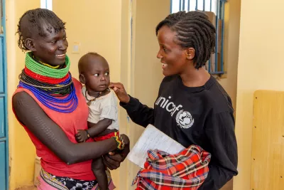 On 8 September 2022 in Kobuin, Turkana County, Kenya, Vanessa Nakate (right) laughs with Asinyoni Ekiru, mother to 14-month-old Papos Alos.