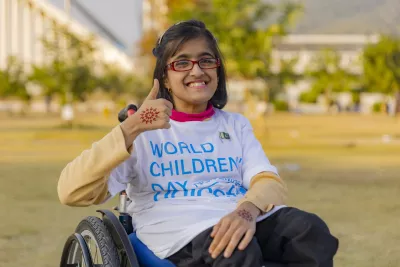 Girl on a wheelchair smiling with thumbs up