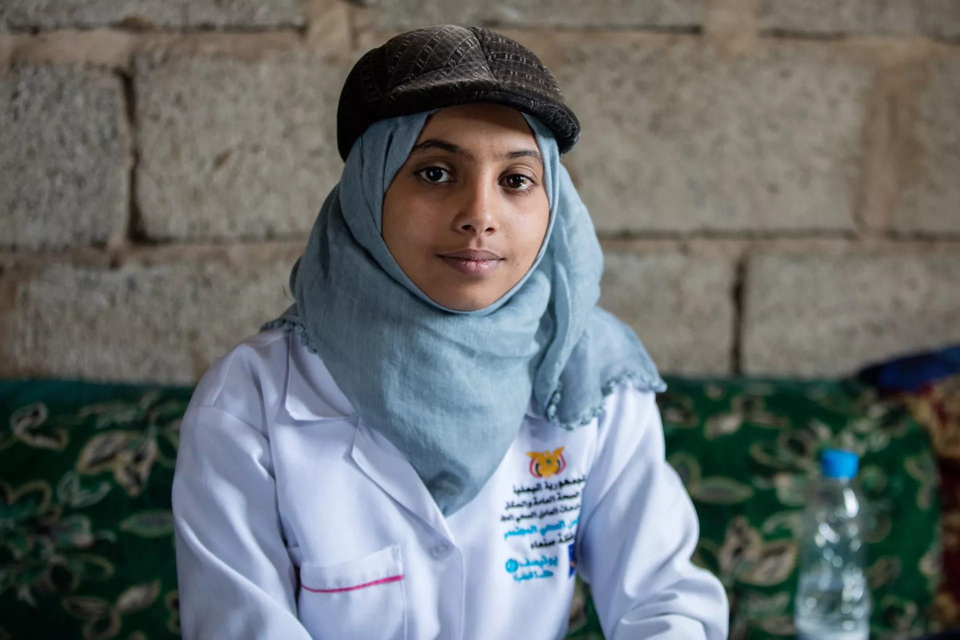 An adolescent community health worker in her medical jacket poses for a photo.