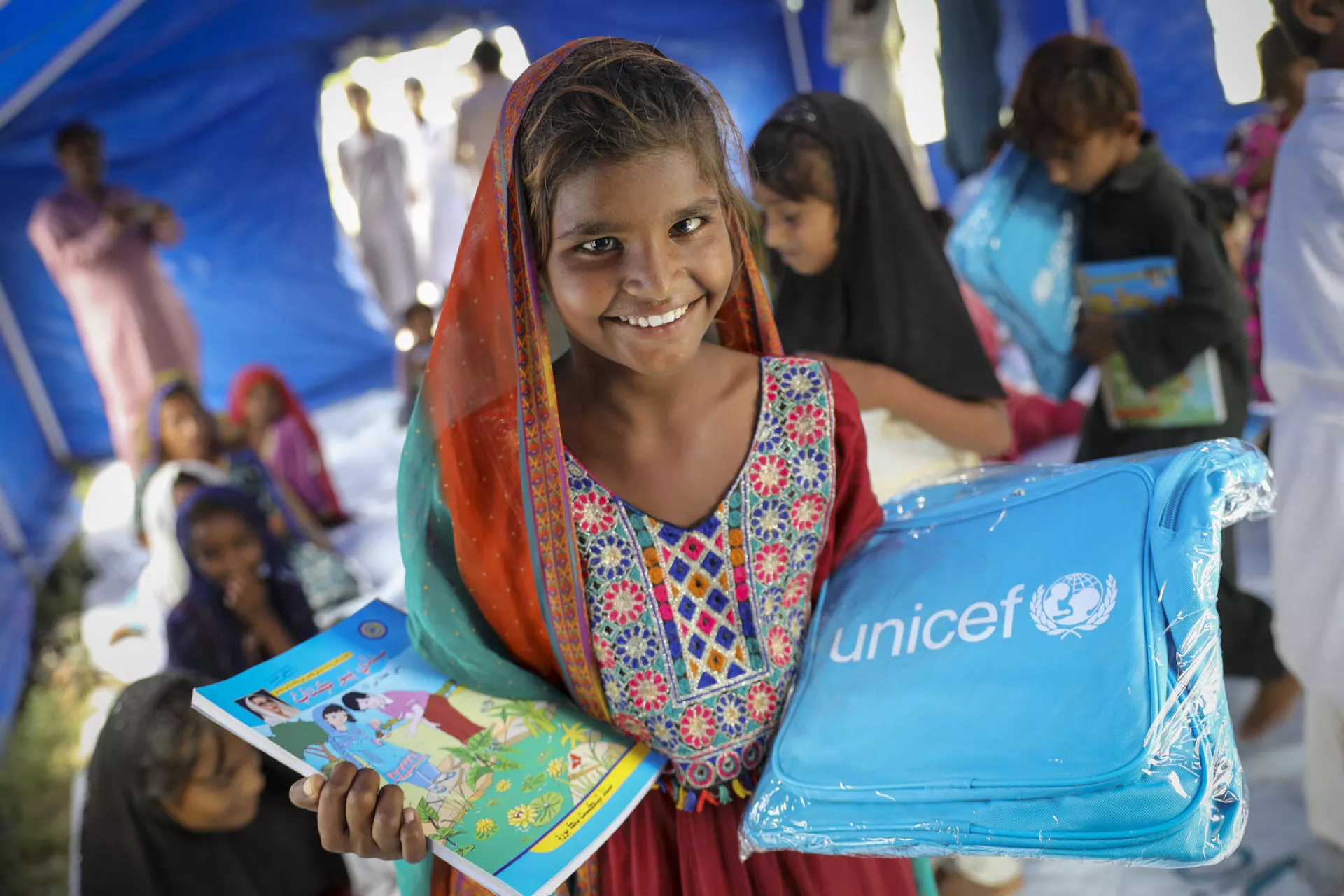 A girl receives a UNICEF bag and books during as part of support provided to flood affected children in Pakistan in 2022.