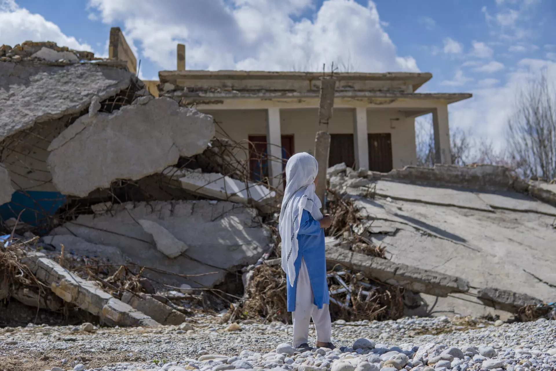 Pakistan. A girl stands near a school destroyed by the floods in Quetta District, Balochistan.
