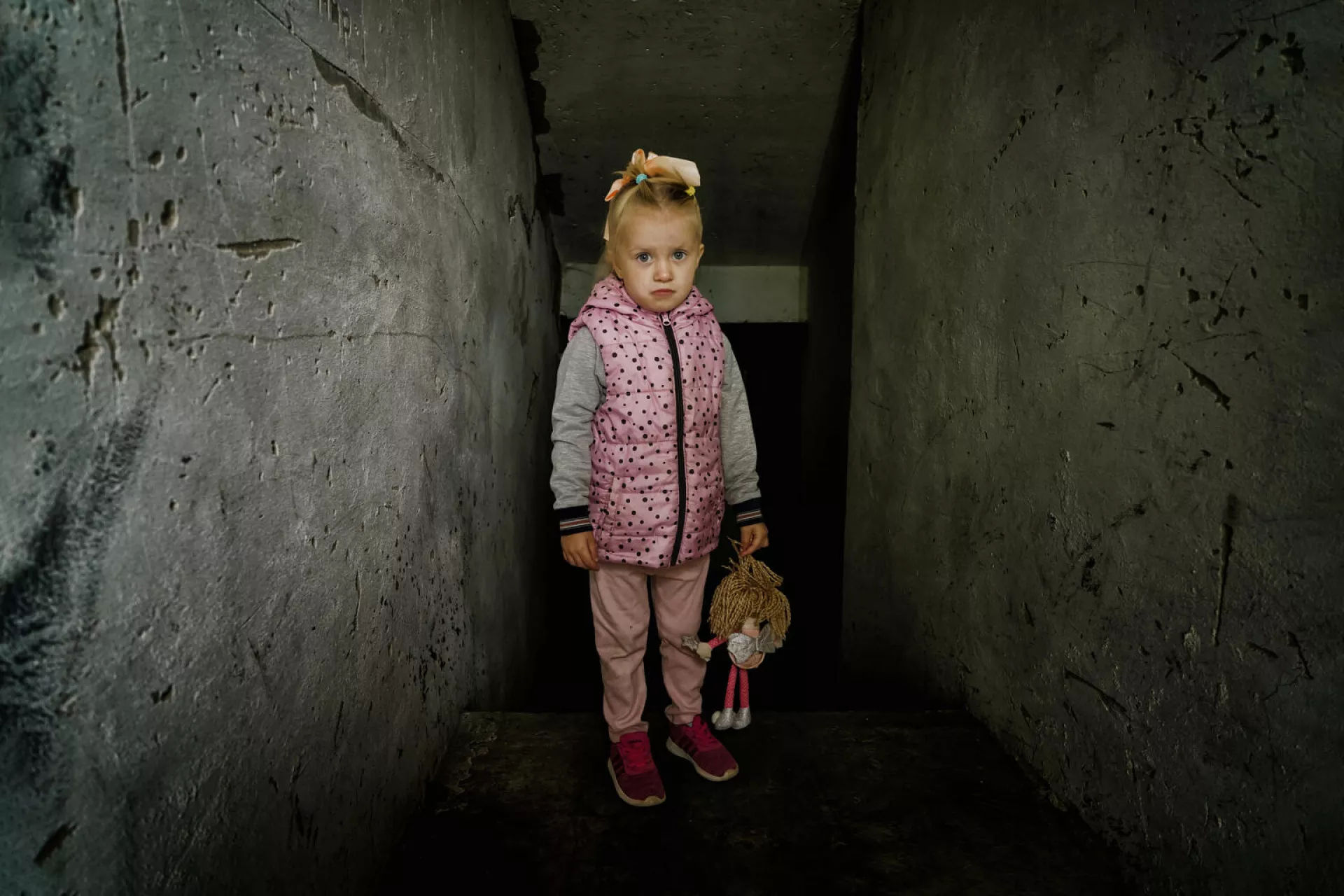 Ukraine. A girl stands in front of the destroyed boiler room at her kindergarten.