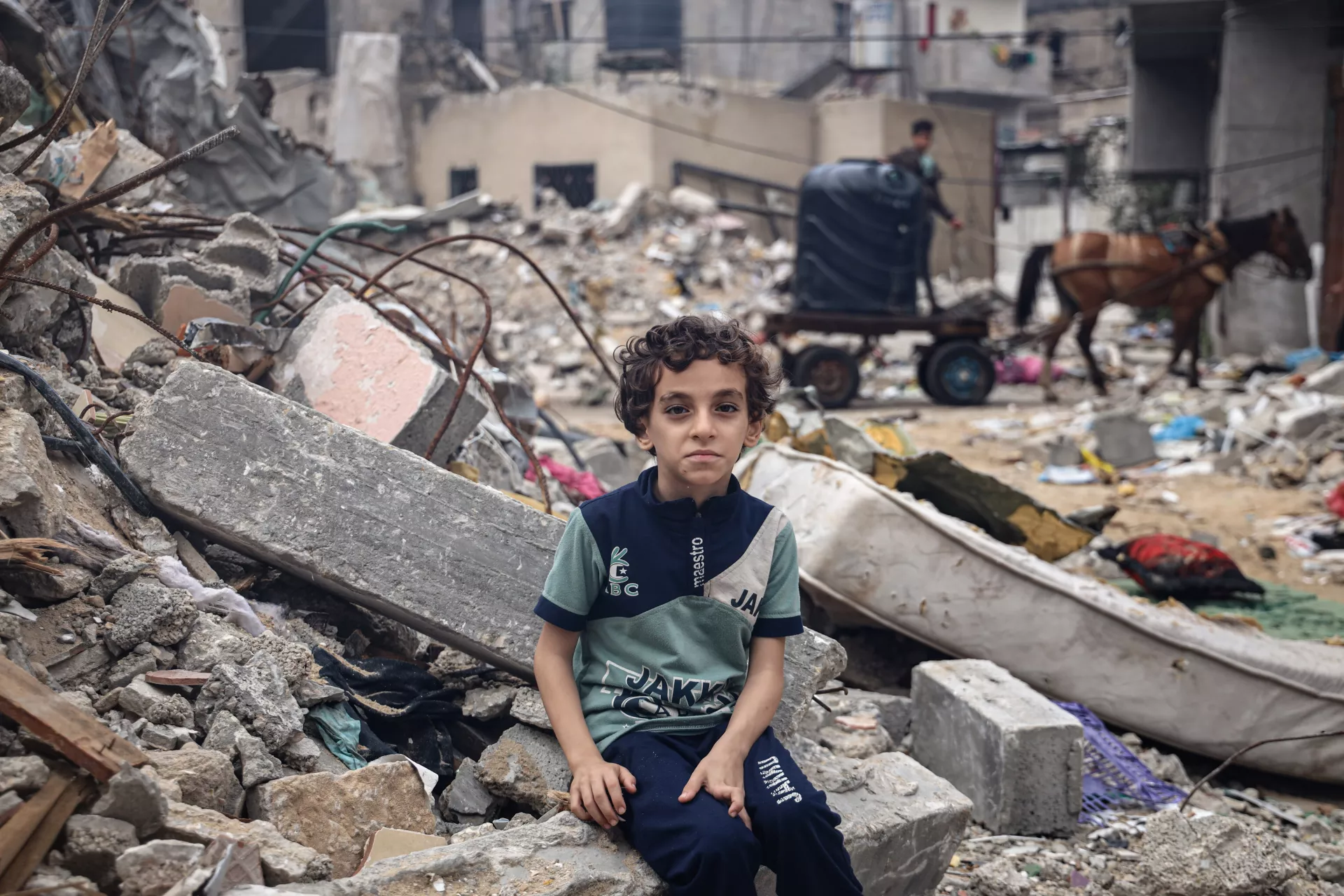 Mohammed Alattar, 8-year-old from Rafah City, sits on the rubble of his family's house, which was bombed in an Israeli airstrike.