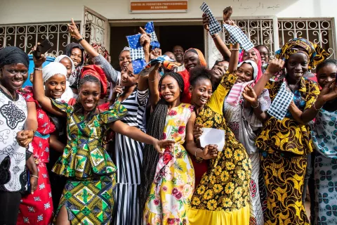 Women standing in jubilation outside an education centre in Senegal