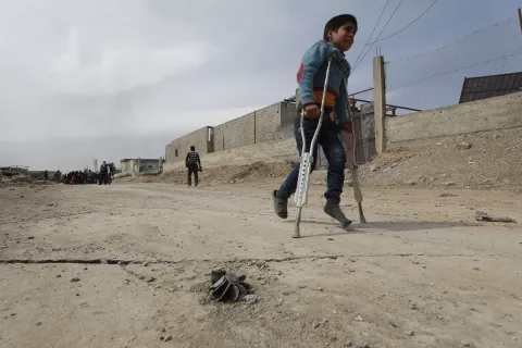 Un garcon marche avec des béquilles dans une rue, Syrie. 