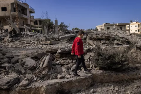 في 22 شباط/فبراير 2024، طفل لبناني يسير بين أنقاض منزل دمرته غارة جوية في مجدل زون، جنوب لبنان.