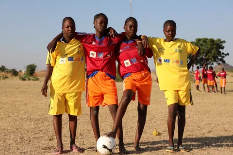 Cameroon. Young football players stand on a pitch.
