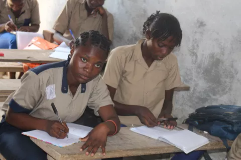 A girl writes in a notebook at her desk, Republic of Congo
