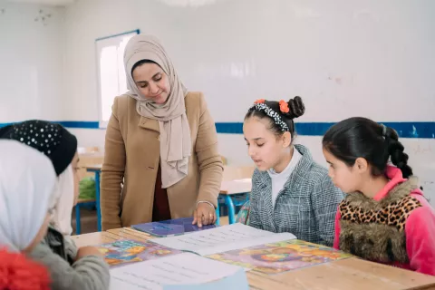 Female teacher helps student learn in classroom. 