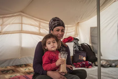 Une femme et sa fille sont assises sous une tente, dans une camp de réfugiés en Iraq, en 
