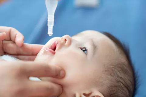 A one-month-old receives an oral vaccination.