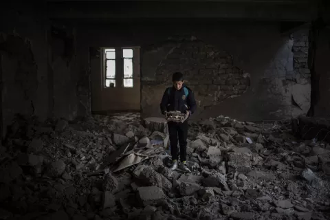 Yousef holds destroyed books at Jummuria Secondary School in Iraq.