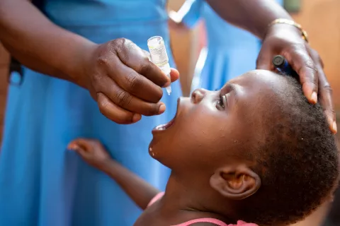 Matilda Mlumpwa, health surveillance assistant (HSA) administers a dose of Oral Polio Vaccine to 3-year old Maria Mphetso