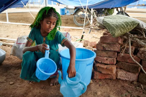 A girl collects water in jerry cans.