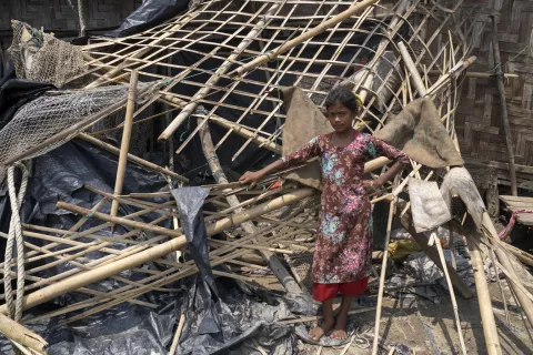 A child stands in their home which is damaged due to a cyclone.
