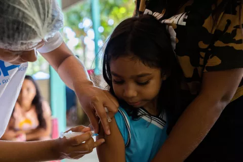 Una niña se mira el brazo mientras recibe una vacuna.