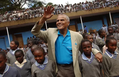 UNICEF Goodwill Ambassador Harry Belafonte waves to onlookers, standing amidst a crowd of children at the Kihumbuini primary school in Kangemi, a poor neighbourhood in Nairobi, the capital