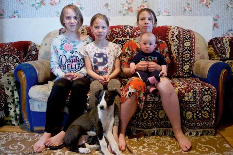 Yana, 12 ans, Lyubov, 10 ans, Arina, 13 ans et Daniil, 7 mois, sont assis dans le salon de leur petite maison louée à Nur-Sultan, au Kazakhstan.