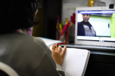 فتاة تدون ملاحظات أثناء فصل دراسي عبر الإنترنت على جهاز الكمبيوتر في المنزل.