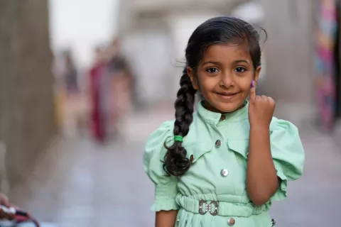 فتاة صغيرة فخورة تعرض إصبعها الملوّن بعد تلقيها اللقاح المضاد لشلل الأطفال في اليمن.