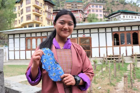 A young girl holds a sanitary napkin