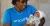A woman in a blue UNICEF t-shirt holds a baby 