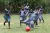 Girls in blue school uniforms play football in the grass.