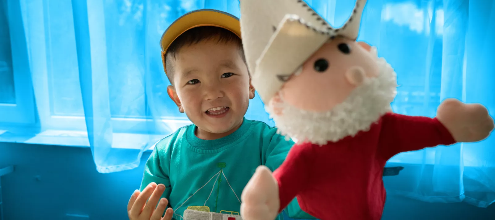 صبي مبتسم يحمل لعبة طرية - قرغيزستان.