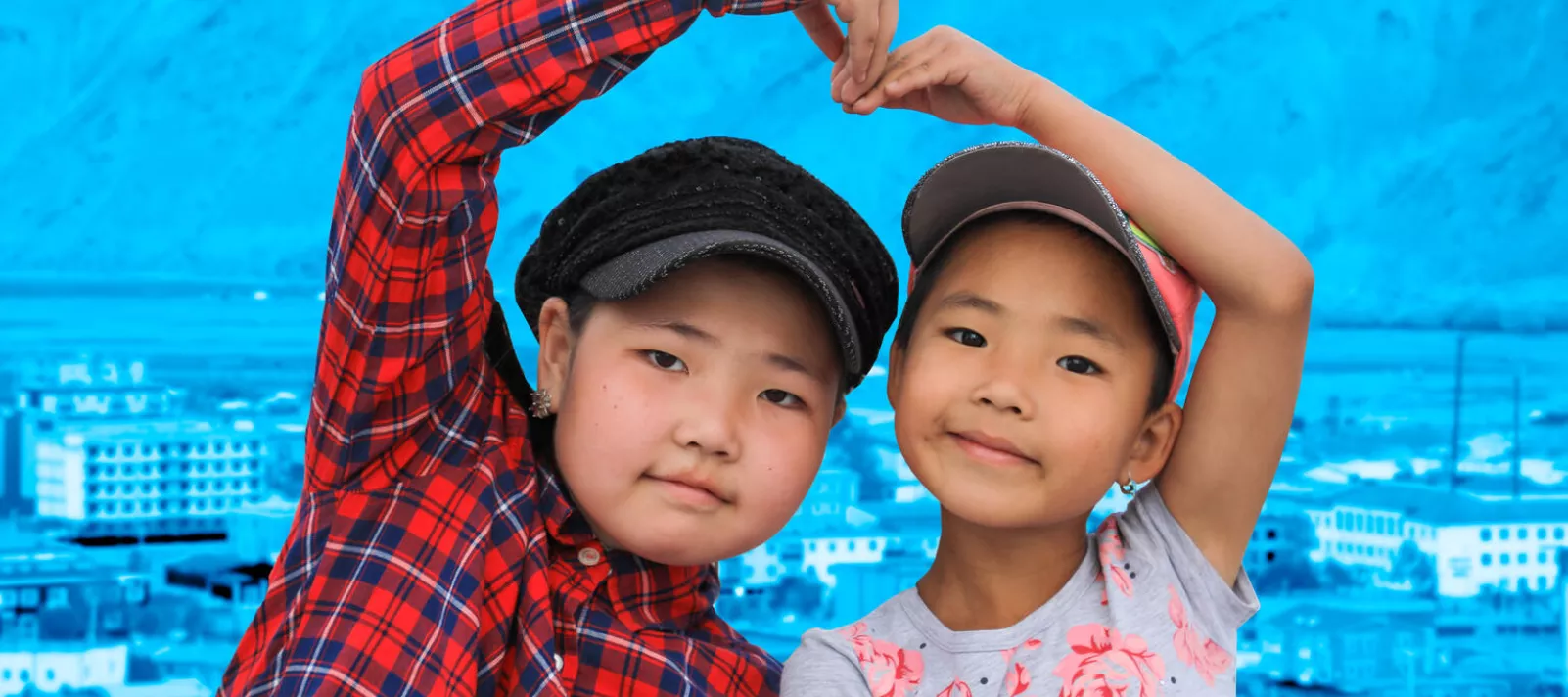Children in Mongolia, 2020, form a heart with their arms.