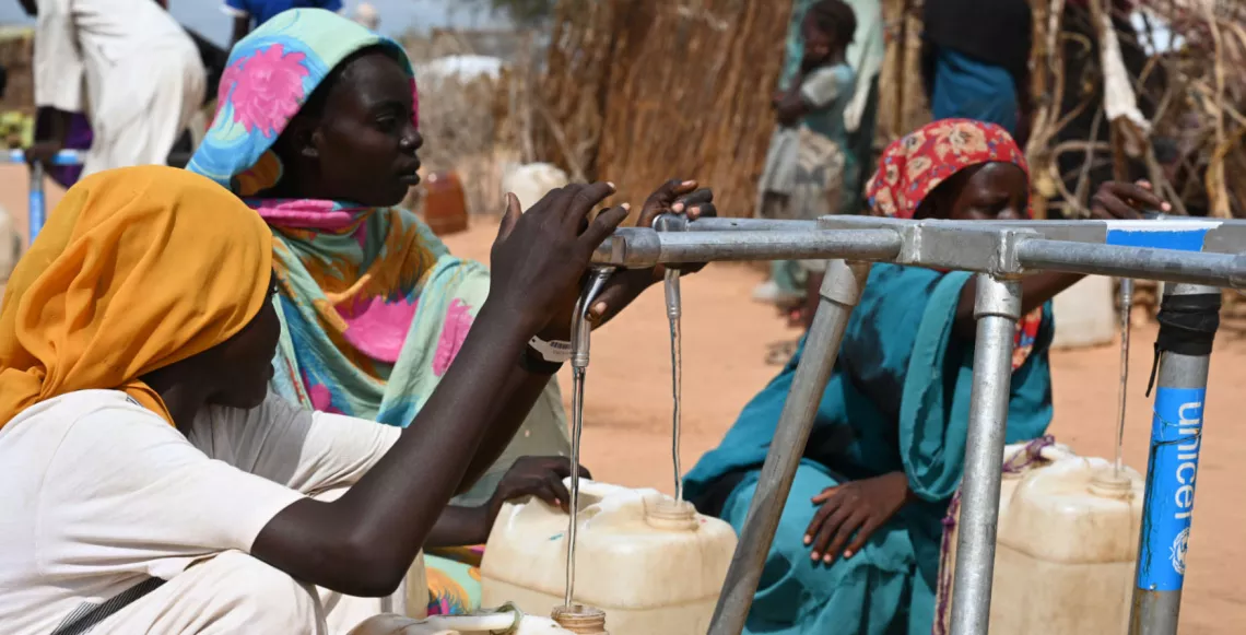 Women and girls collect water at a water point