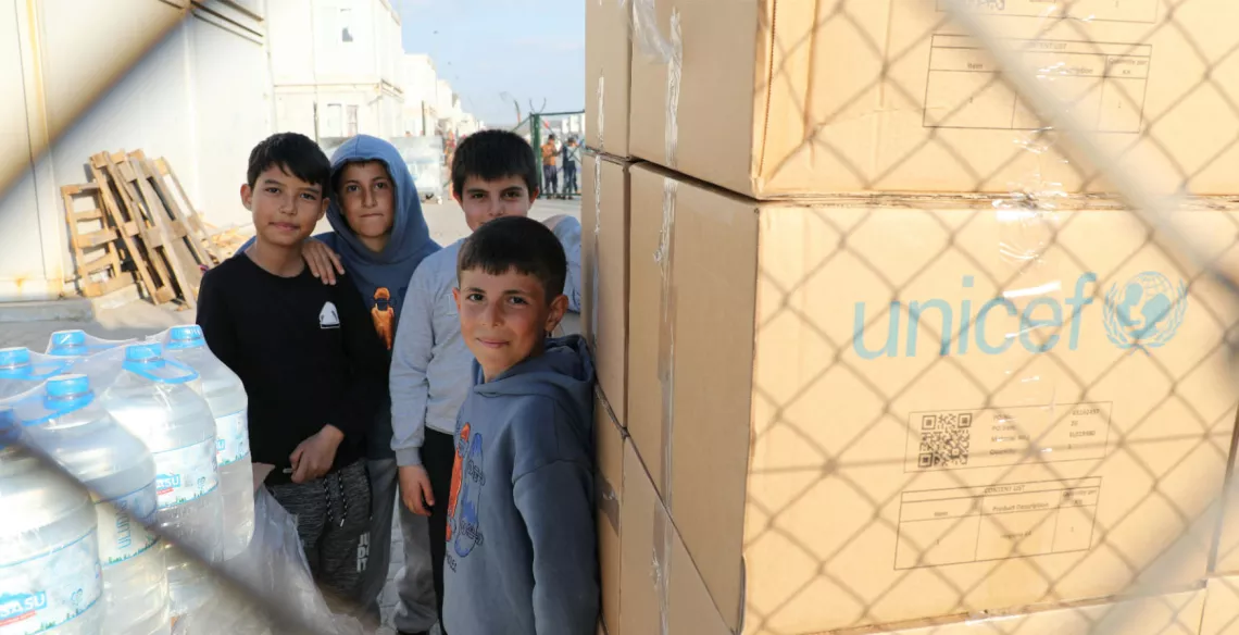 Young boys stand next to supplies delivered by UNICEF