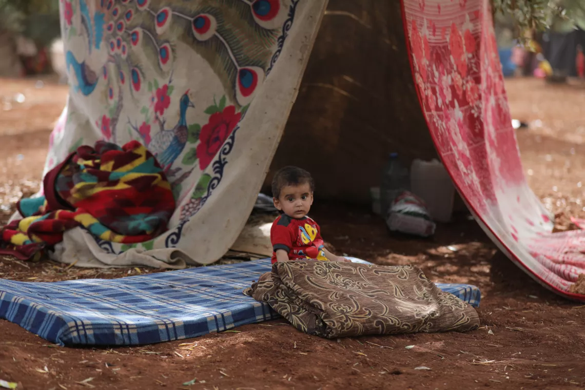 Syria. A small child sits under a makeshift tent.