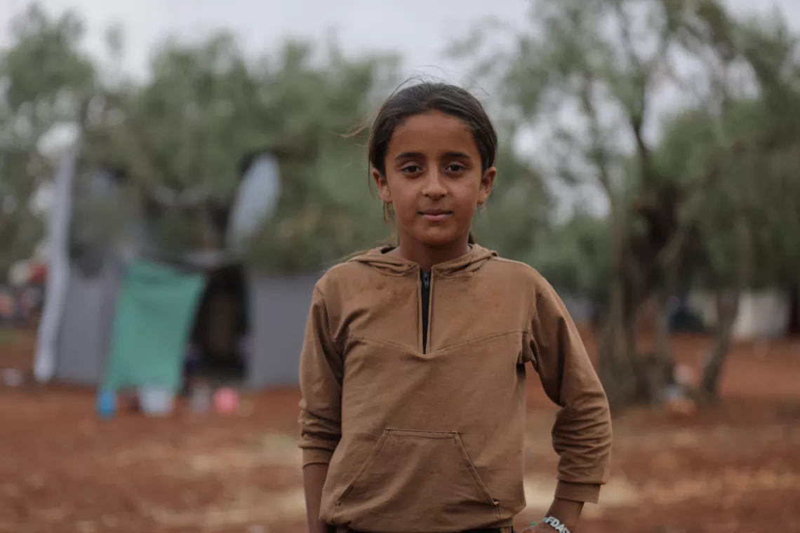 Syria. A girl stands near a makeshift camp near the border with Turkey.