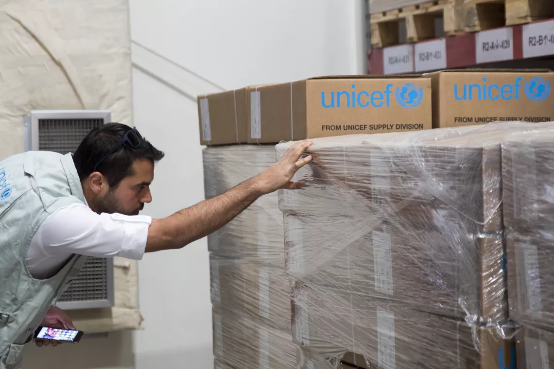 A  logistics officer inspects boxes of health and nutrition supplies in a warehouse.
