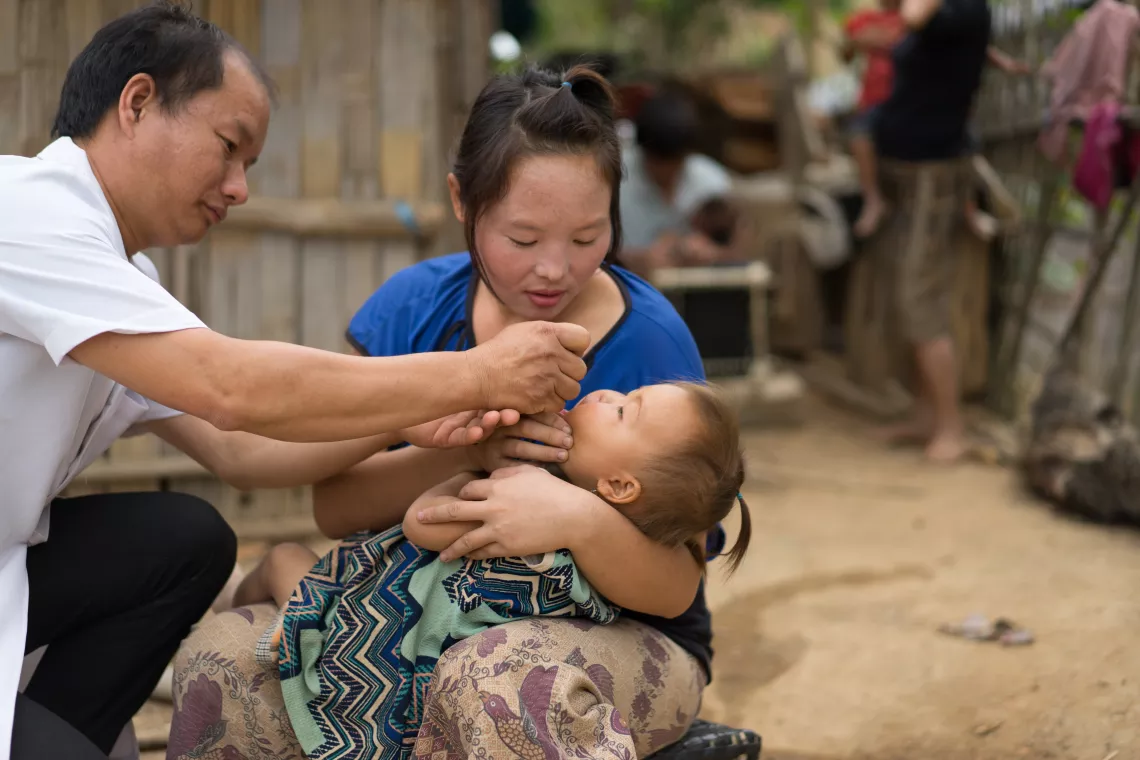 A mother holds her baby as she receives vaccination from a local health worker.