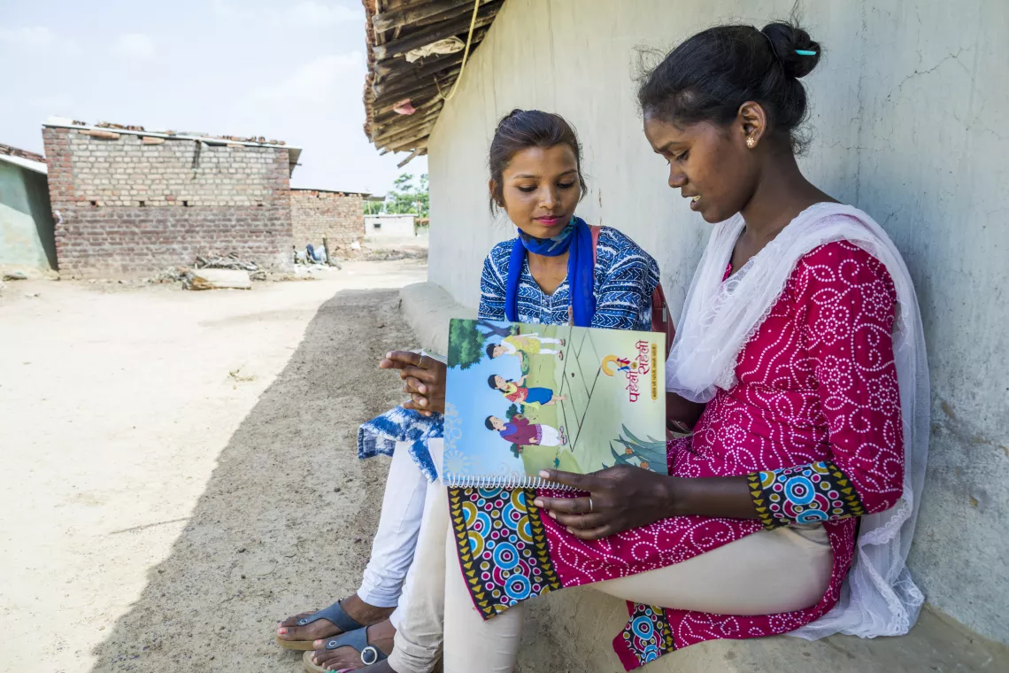 Two teenage girls look at a pamphlet, India. 