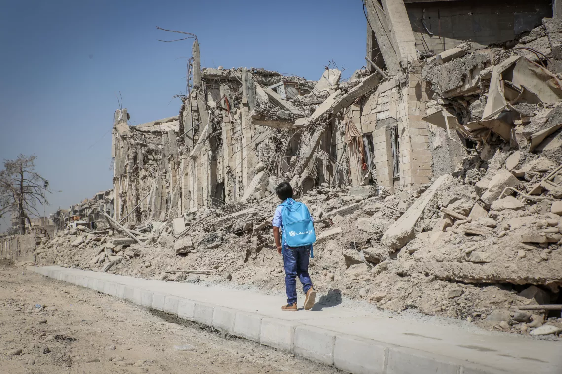 A child walks past damaged buildings in Iraq.