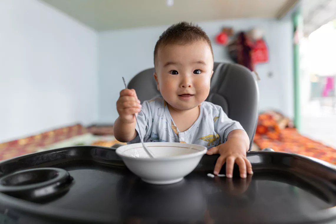 Nurislam, 13 months, eats porridge at home in Kurshab village, Uzgen district, Osh Oblast, Kyrgyzstan.