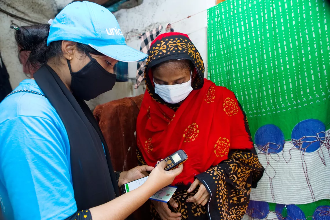 UNICEF volunteer Mukta helps a community member to register for a COVID-19 vaccine on her mobile phone.