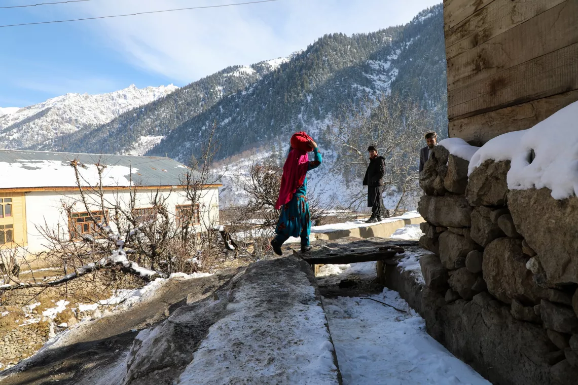 Afghanistan. A girl carries her freshly washed clothes on her head as she walks home. In Parun, Nuristan Province, locals use water from a nearby to wash their clothes.