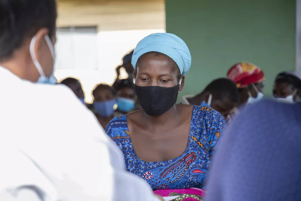 Neema Kabiringi speaks to a health care worker about the COVID-19 vaccine.