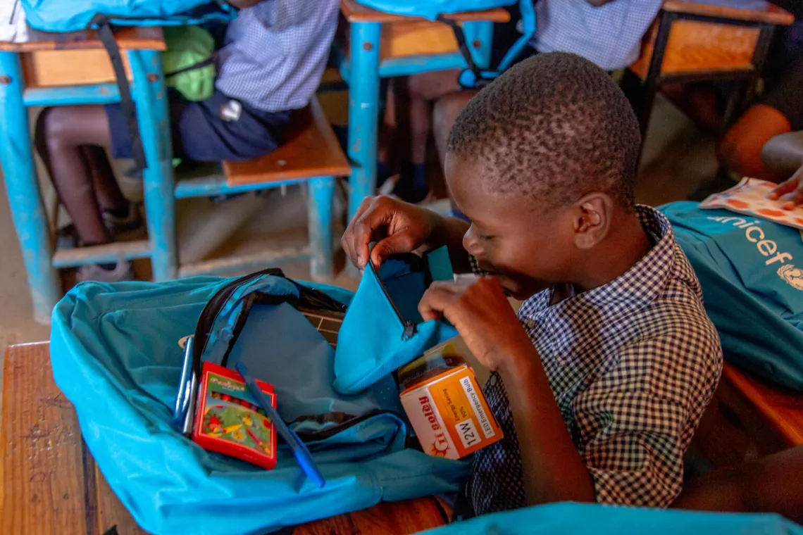 Haiti. A boy opens a bag containing school supplies.