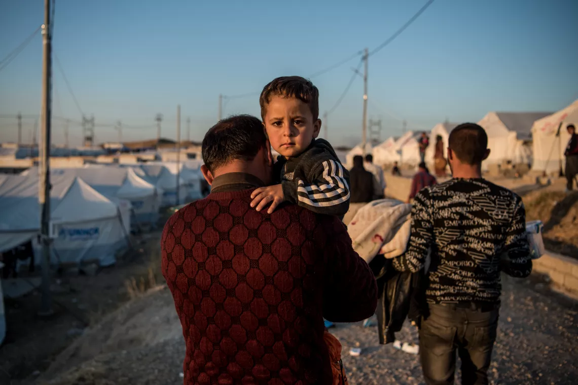 Iraq. A man carries his son to their tent in the Bardarash camp near the city of Dohuk.
