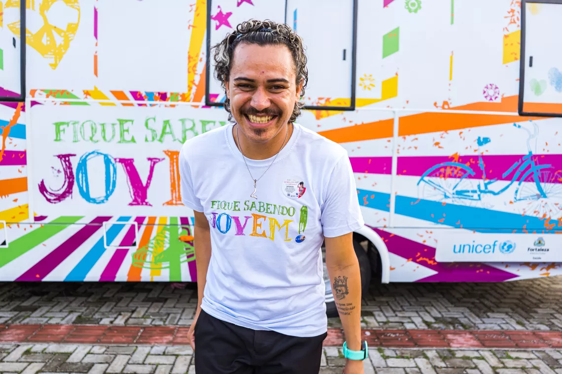 Smiling young man in front of a brightly painted bus.